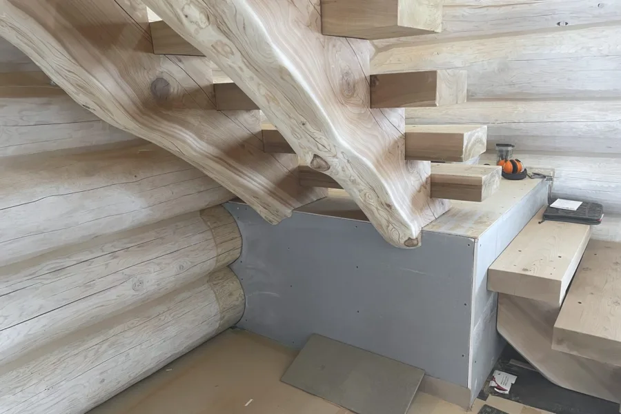 Stair treads mortised into a single curved log stringer in a log home