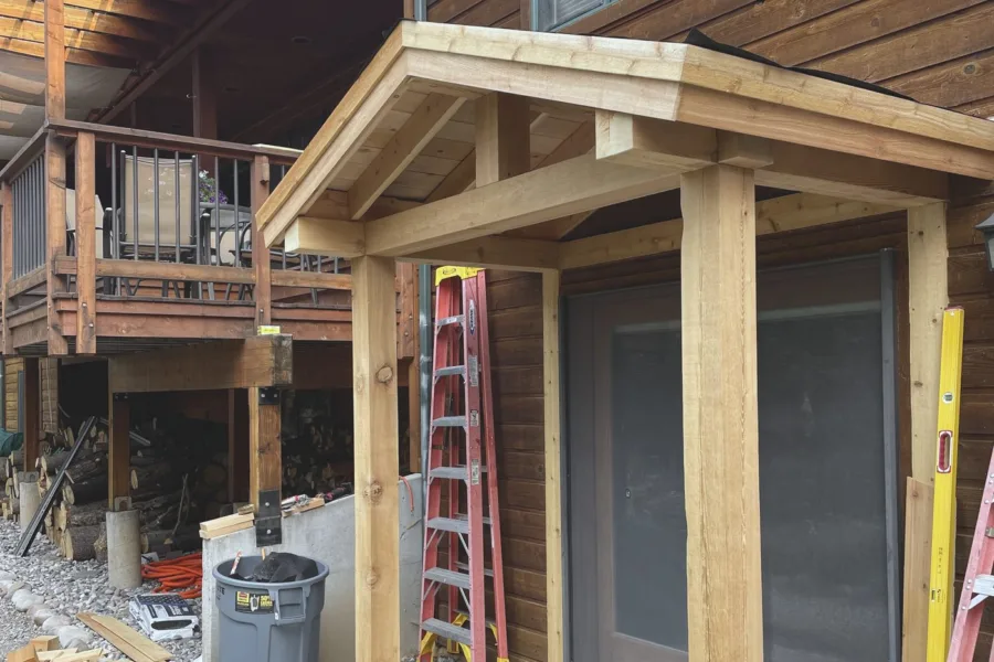 A timber framed entry portico on a log home, roof deck on and trim complete