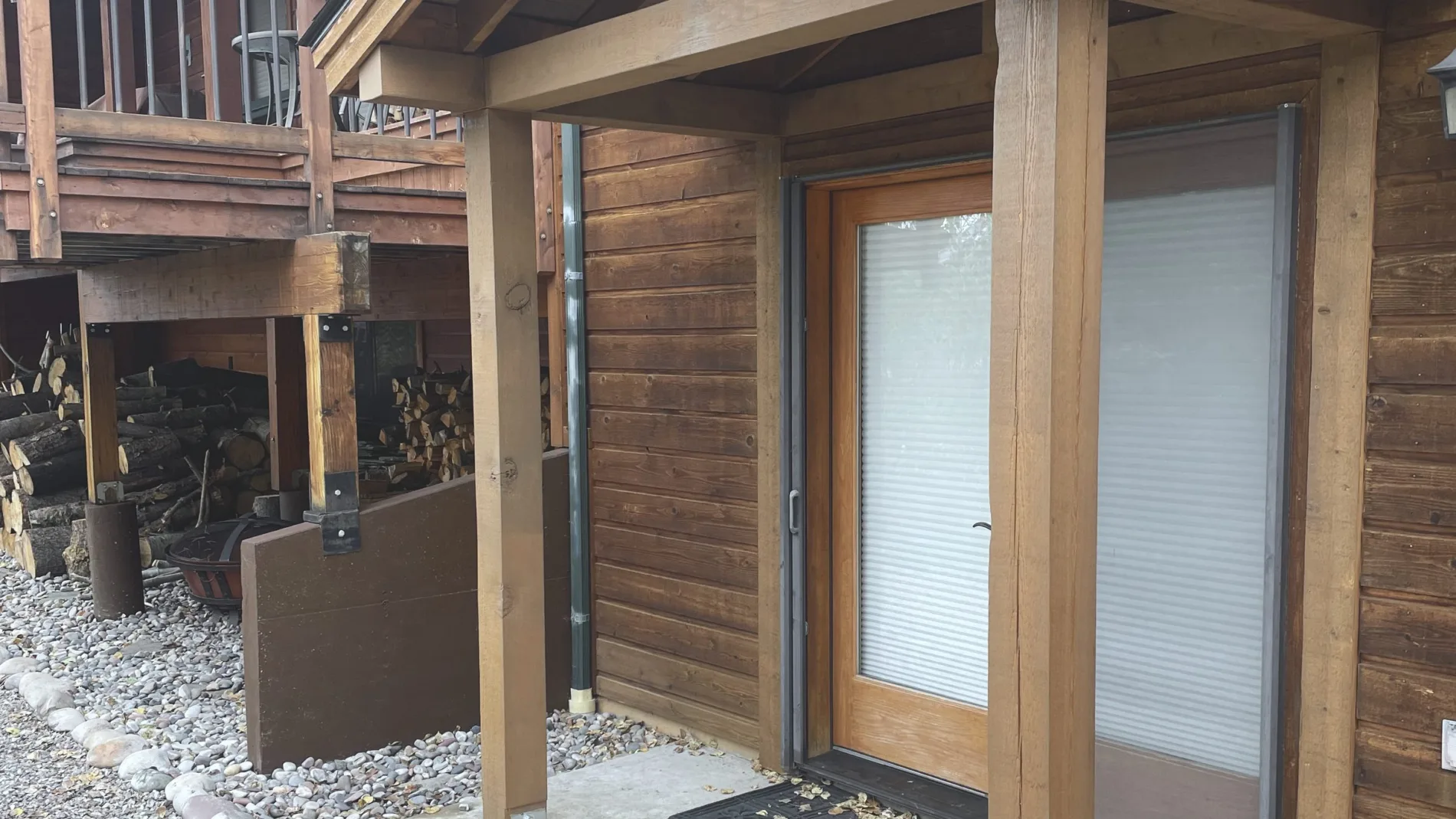 A finished timber entry portico on a log home, stained with a standing seam roof