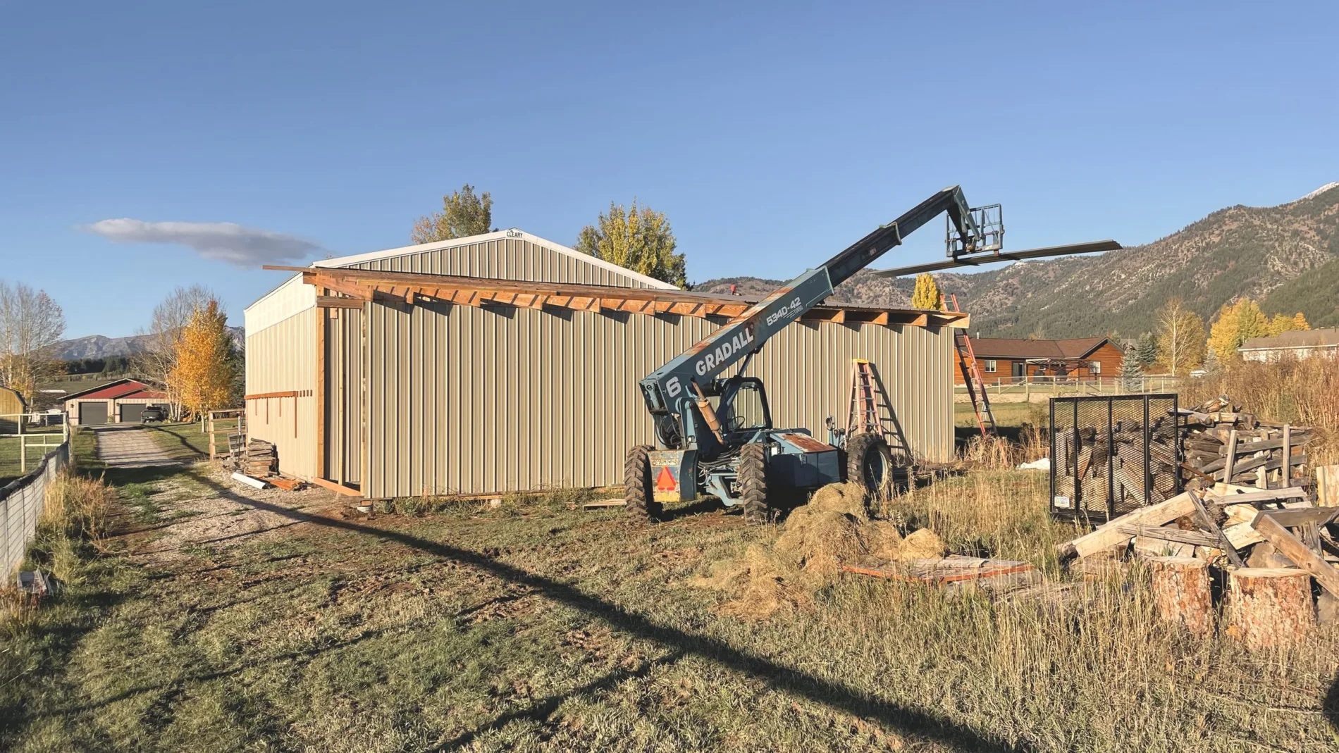 A timber framed covered bay being added to a metal building, telehandler on site